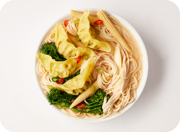 A bowl of ramen soup with dumplings, noodles, broccoli, baby corn, and chili.