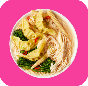 Bowl of Asian noodle soup with dumplings, baby corn, broccoli, and red chili slices.