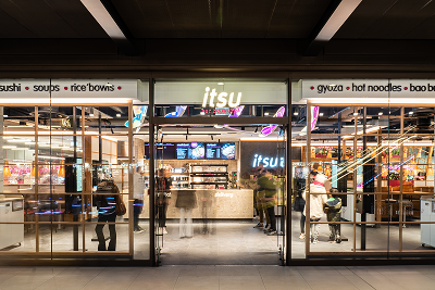 Modern Itsu restaurant storefront with glass facade and warm interior lighting.