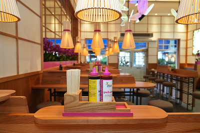 Restaurant interior with wooden tables, pink accents, and a condiment caddy.