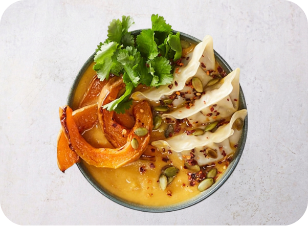 Creamy orange soup topped with roasted squash, dumplings, fresh cilantro, and chili flakes.