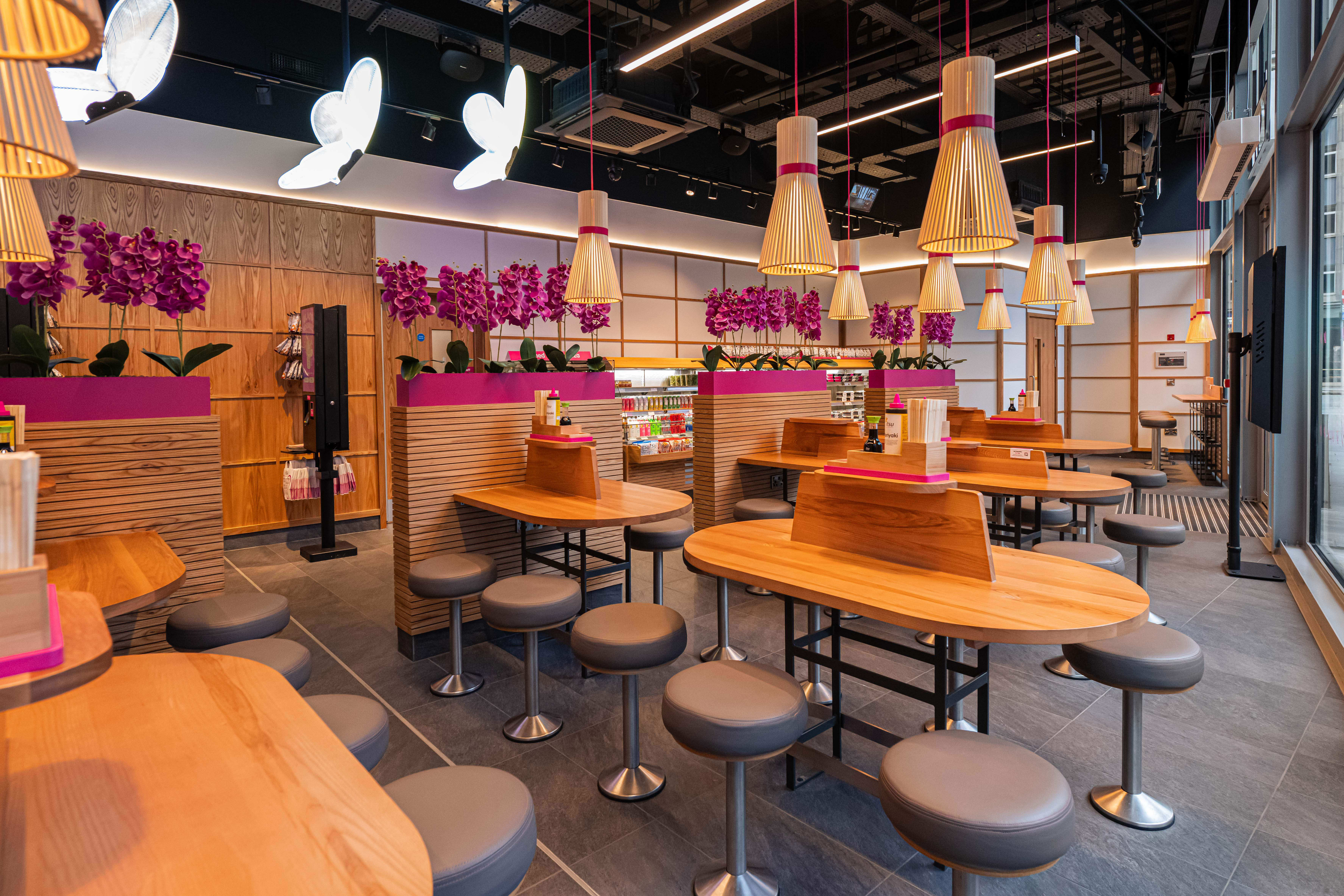 Stylish modern cafe interior with wooden tables, grey stools, and unique butterfly lights.