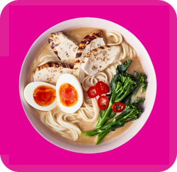 Overhead view of ramen bowl with grilled chicken, soft-boiled egg, broccoli, and tomatoes.