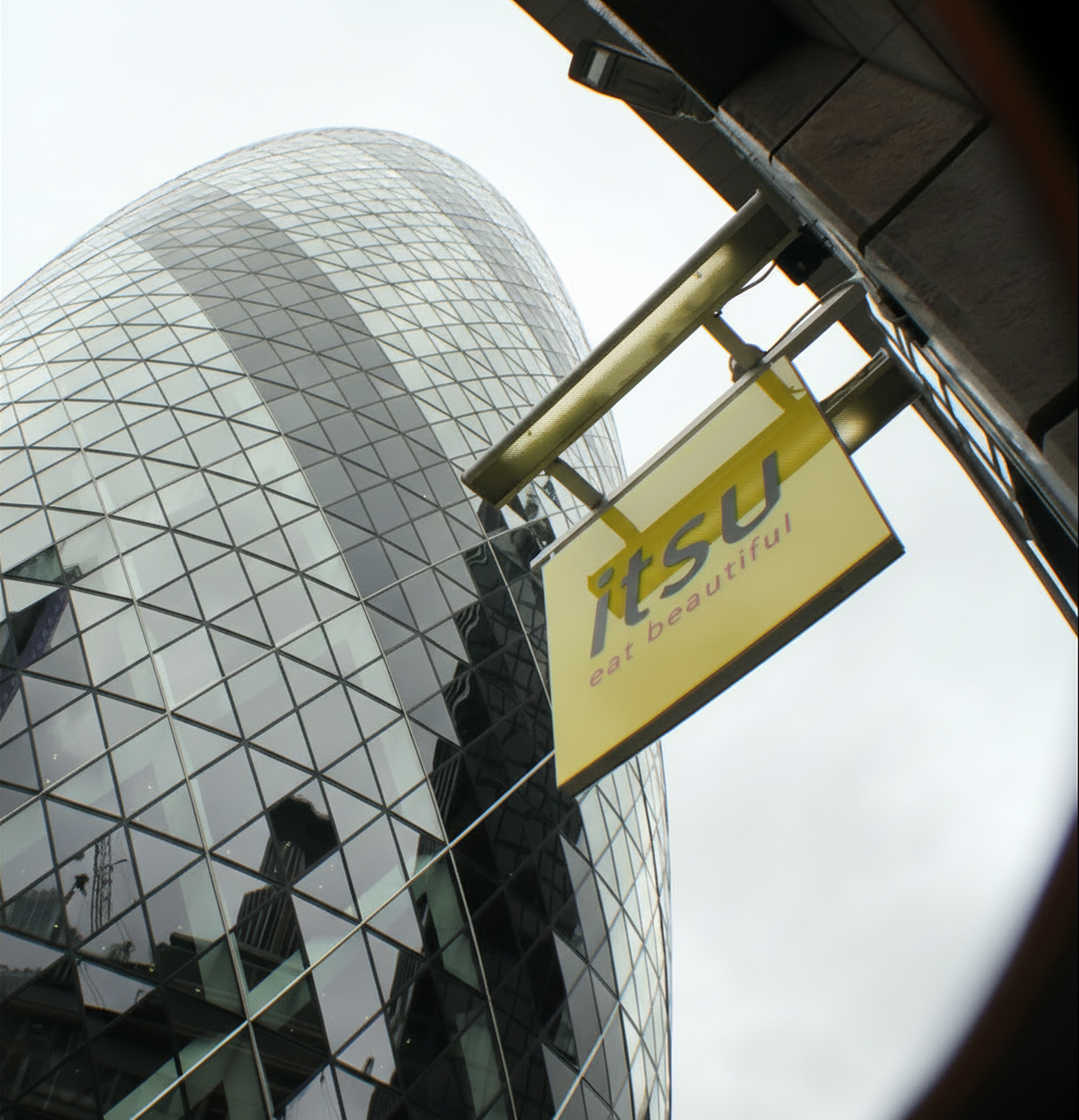 The Gherkin building, a curved glass skyscraper, next to a yellow 'ASU Bar & Restaurant' sign.