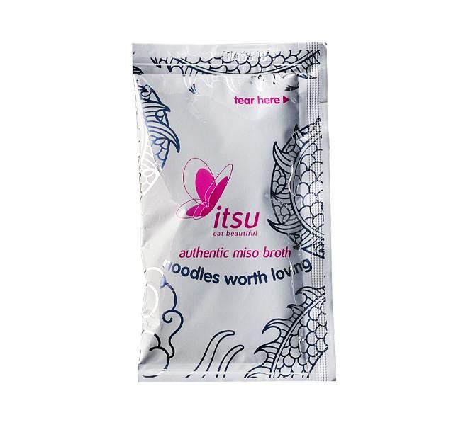 Silver Itsu sachet for authentic miso broth with 'noodles worth loving' text.
