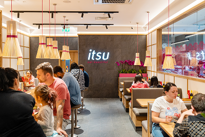 Busy interior of an itsu restaurant with patrons dining at tables and a counter.