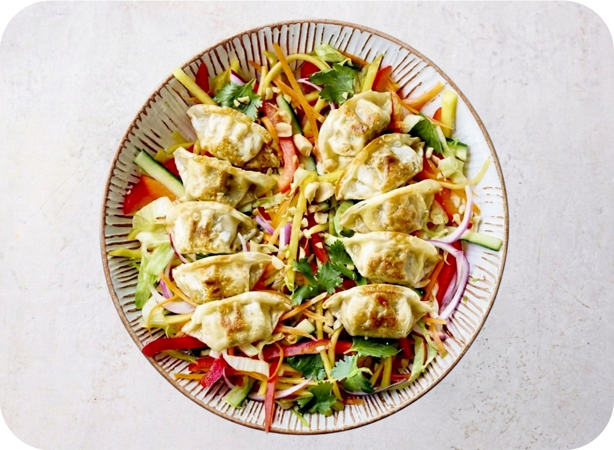 A vibrant Asian-inspired salad with shredded vegetables, herbs, peanuts, and crispy fried dumplings.