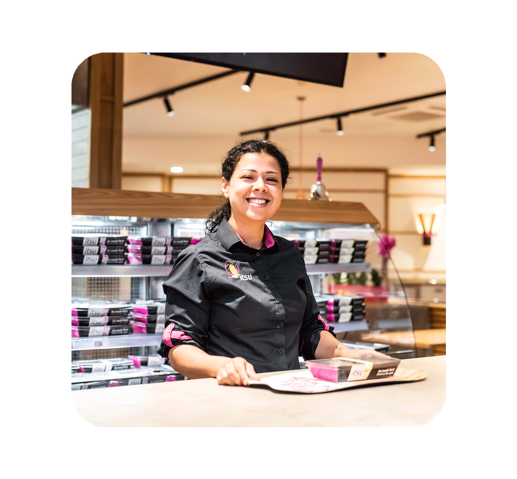 Smiling woman in uniform standing behind a counter in a retail store.