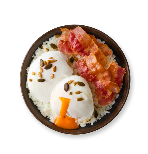 Bowl of white rice topped with two poached eggs, crispy bacon, pumpkin seeds, and pine nuts.