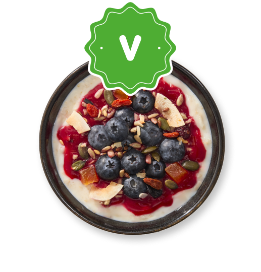 Vegan porridge bowl with blueberries, seeds, goji berries, coconut flakes, and raspberry swirl.