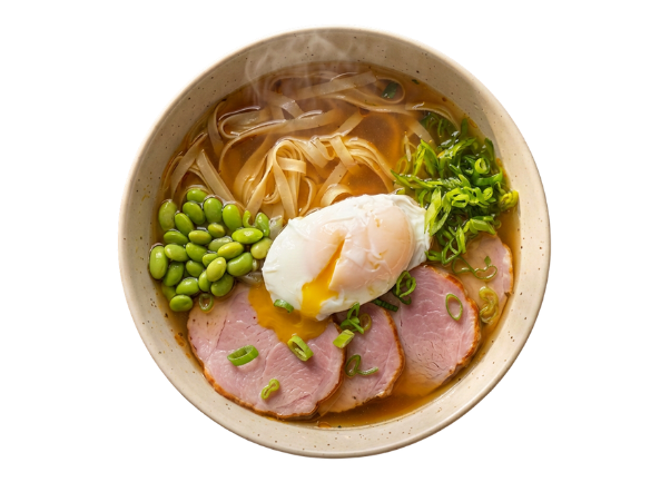 Bowl of ramen with noodles, sliced ham, a runny poached egg, edamame, and green onions.