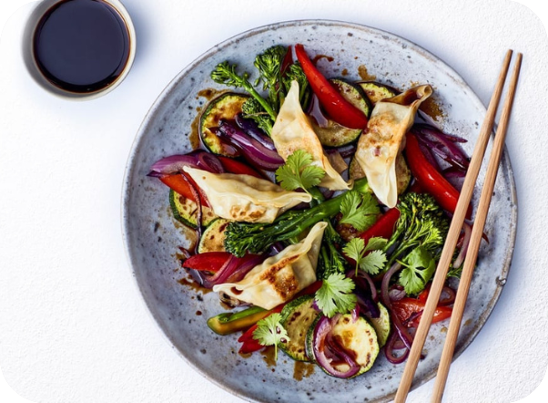 Stir-fried vegetables with gyoza dumplings, broccoli, zucchini, peppers, and soy sauce.
