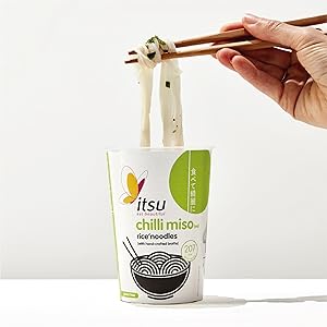 Hand pulls noodles with chopsticks from an Itsu chilli miso cup.