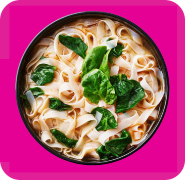 A dark bowl holds flat noodles in broth, garnished with fresh green spinach leaves.