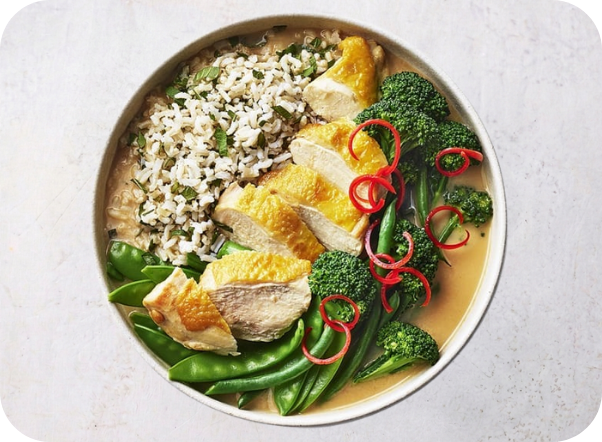 Sliced chicken, wild rice, broccoli, snap peas, and red chilis in a savory broth bowl.