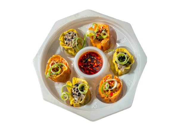 Six vibrant dumplings garnished with green onions and served with chili oil on a white plate.
