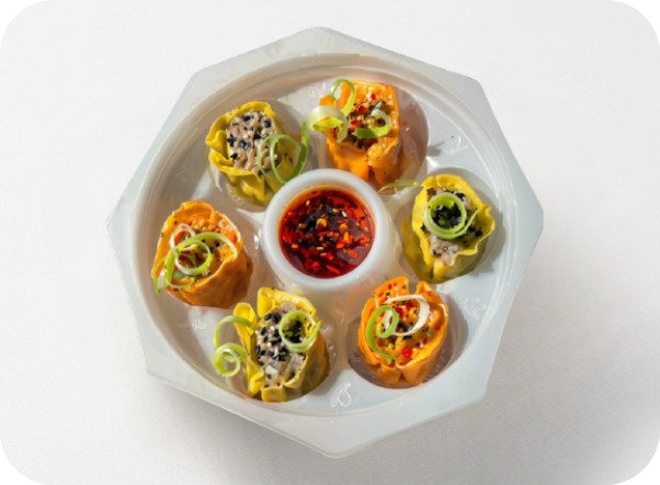 Colorful dumplings arranged around a chili dipping sauce on a white plate.