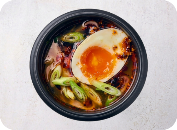 Spicy ramen bowl with a soft-boiled egg, green onions, and rich broth.