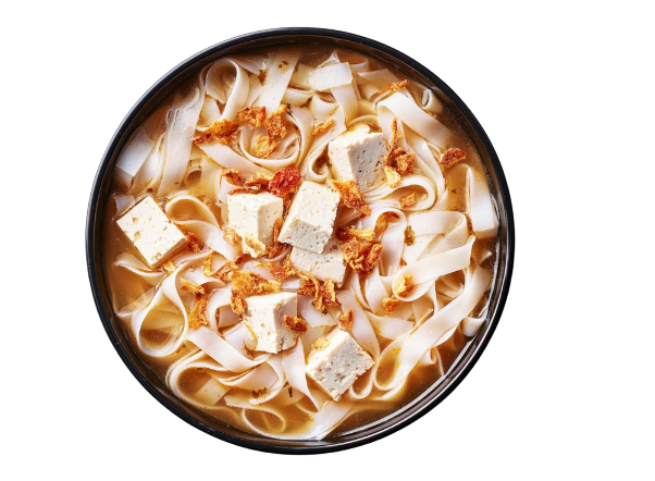 Bowl of flat rice noodles with tofu cubes and crispy fried shallots in broth.