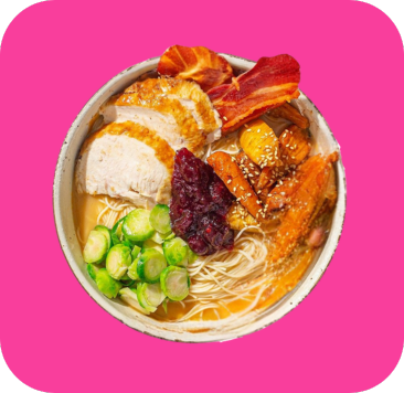 Ramen bowl with sliced chicken, crispy bacon, roasted vegetables, Brussels sprouts, and cranberry sauce.