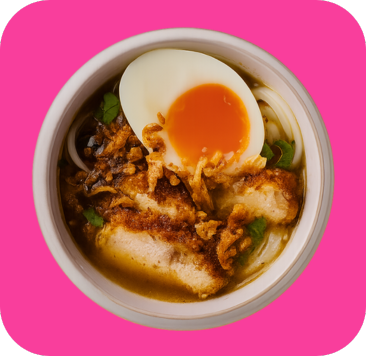 A bowl of noodle soup with crispy fried chicken, soft-boiled egg, and garnishes.