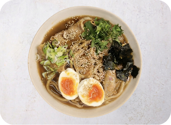 Overhead view of a delicious ramen bowl with soft-boiled eggs, sliced pork, noodles, and seaweed.