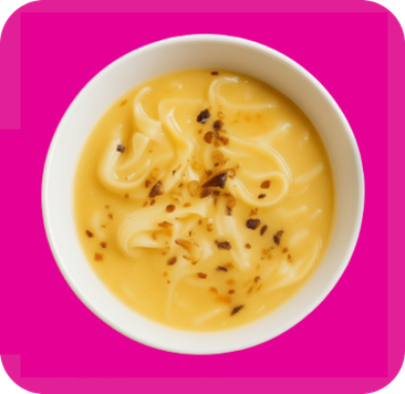 Creamy yellow noodles topped with red chili flakes in a white bowl from above.