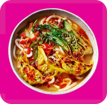 Spicy noodle soup with dumplings, bok choy, and red peppers in a colorful bowl.