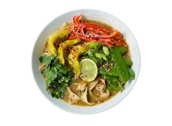 Vibrant ramen bowl topped with colorful bell peppers, snap peas, cilantro, and a lime.
