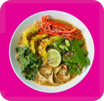 Vibrant bowl of ramen with colorful bell peppers, snap peas, cilantro, and a fresh lime wedge.