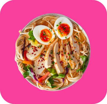 A bowl of ramen with sliced chicken, soft-boiled eggs, noodles, and fresh vegetables.