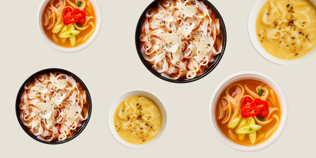 Multiple bowls of Asian-style noodle soups with various toppings like peppers, onions, and cheese.