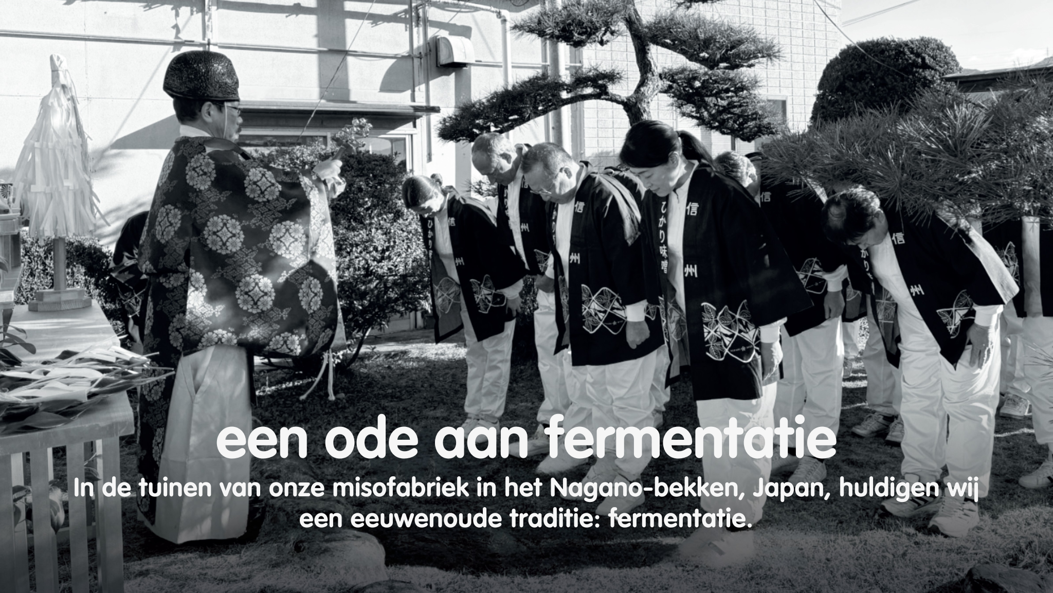 Japanese people in traditional robes bowing during a ceremony, with text "een ode aan fermentatie".