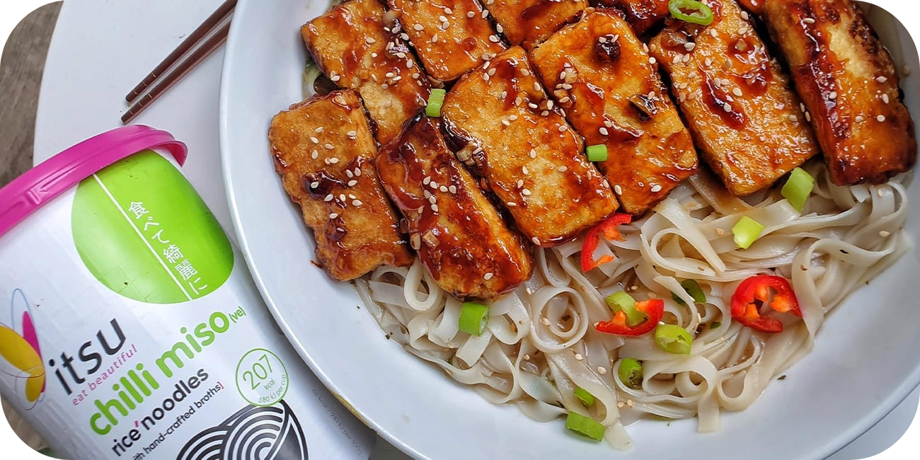 Glazed tofu, rice noodles, green onions, and chili with an Itsu chilli miso noodle pot.