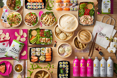 Overhead view of a large spread of Itsu sushi, dumplings, salads, drinks, and snacks.
