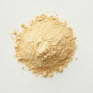 Pile of light brown nutritional yeast powder with a few small granules on a white surface.