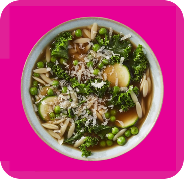 Close-up of a vibrant green vegetable and almond soup in a light blue bowl.