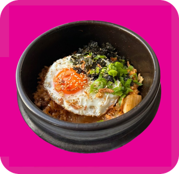 A stone bowl filled with rice, a fried egg, green onions, and dried seaweed.