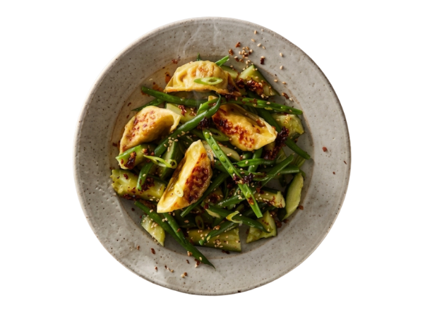 Rustic plate of green beans and seared potato wedges topped with chili flakes.