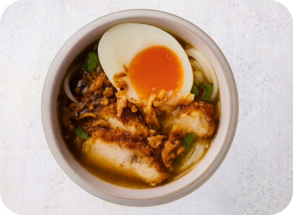 Bowl of ramen with crispy fried chicken, soft-boiled egg, and aromatic broth.