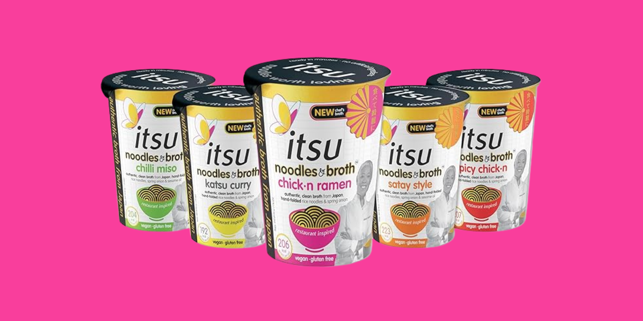 Five itsu brand instant noodle cups in assorted flavors against a pink background.