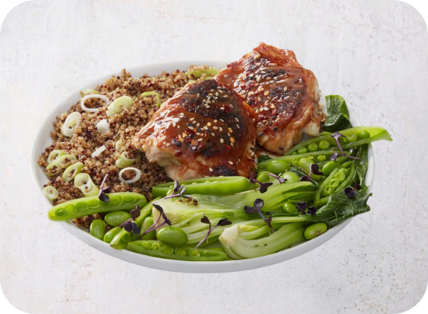 Glazed chicken thighs, quinoa, and fresh green vegetables in a white bowl.