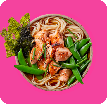 A bowl of salmon noodles with sugar snap peas and nori seaweed.