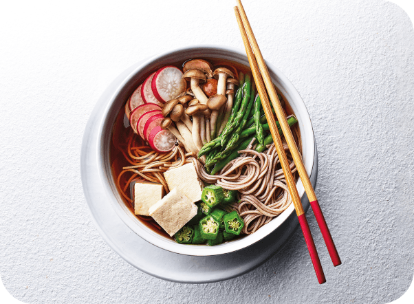 A bowl of Japanese noodles with tofu, mushrooms, asparagus, radishes, and okra.