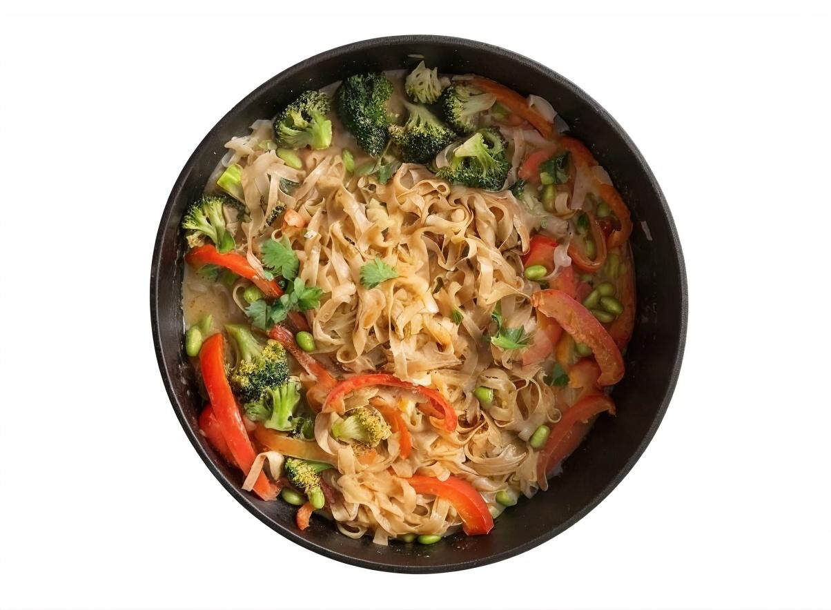 Bowl of stir-fried noodles with broccoli, red bell peppers, and fresh herbs.