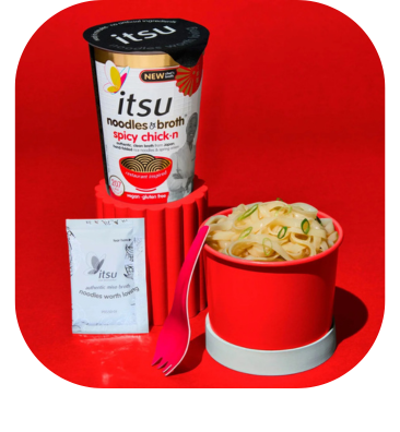 Itsu spicy chick'n noodle cup with a bowl of cooked noodles and a pink spork.