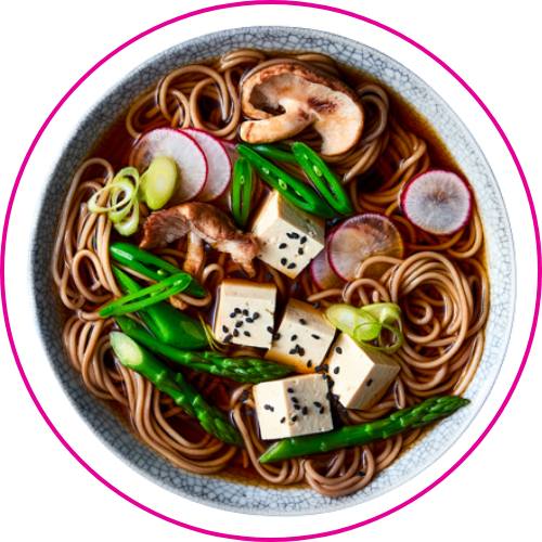 Bowl of soba noodle soup with tofu, mushrooms, radishes, and green asparagus.