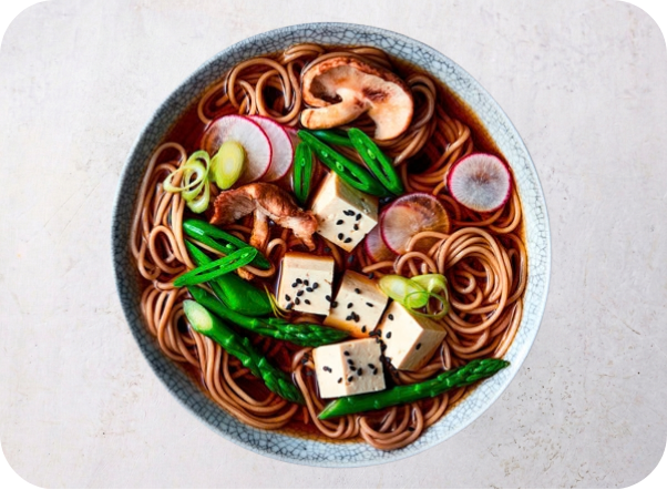Japanese soba noodle soup with tofu, mushrooms, asparagus, radishes, and green onions.