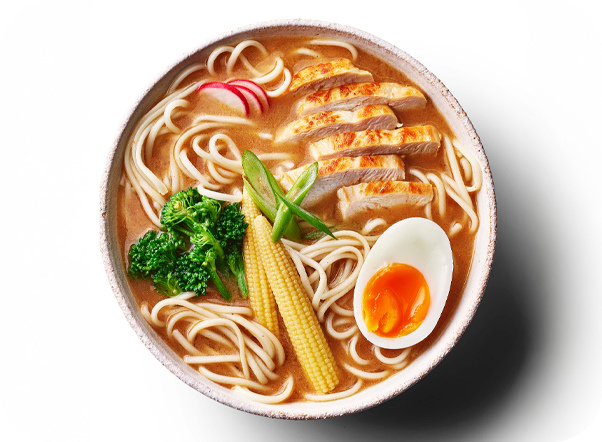 Ramen bowl with sliced chicken, soft-boiled egg, baby corn, and broccoli in savory broth.