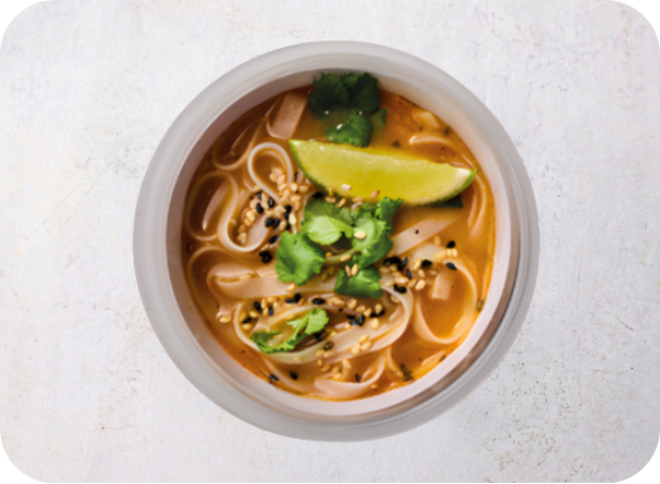 A bowl of flavorful noodle soup with a lime wedge, cilantro, and sesame seeds.